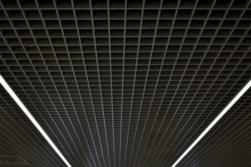 Black trellised ceiling. The illusion of curving lines. Geometric design.LED strip lighting. View from below.