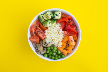 Vegan poke bowl with couscous  and vegetables in the white bowl in the center of the yellow ...