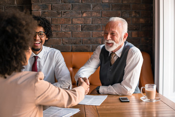 An elderly executive has just signed a contract with an attractive female business partner.