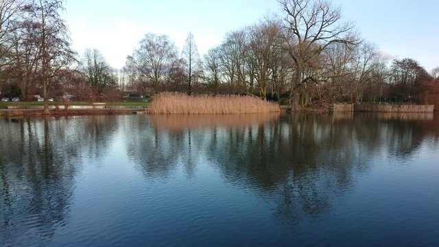 Calm lake water and reflections with trees at the background