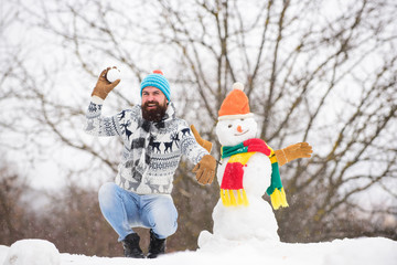 Snowman concept. Man bearded hipster cute knitted hat play with snow outdoors. Have fun frosty...