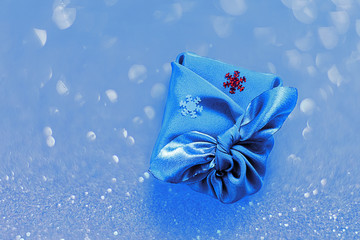 Christmas gift, wrapped in silk fabric, traditional Japanese style, furoshiki, zero waste lifestyle. Concept wrapping. Bokeh effect.