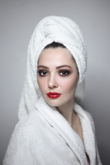 Obraz premium Young beautiful woman with prom makeup wearing white bathrobe and towel turban, soft focus