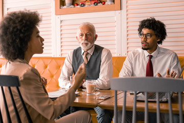 A CEO is about to make an important decisions while his two trusted employees discuss the details and options.