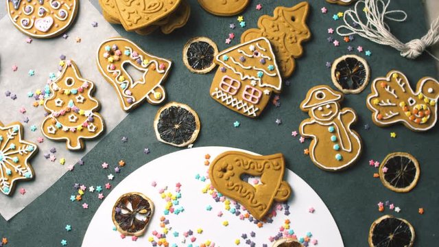 Nice yummy sweet gingerbread cookies with cream and sprinkles decoration on dark texture surface. Christmas holidays food. Close up 4k.