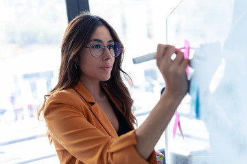 Business young woman working on white board with post it stickers in the office.