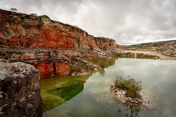 Fototapeta na wymiar A former quarry with red layers of rocks and green water in Minas Gerais states in Brazil