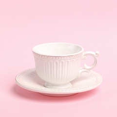 White porcelain cup with saucer on a pink background