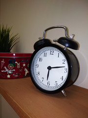 black alarm clock on a wooden shelf
