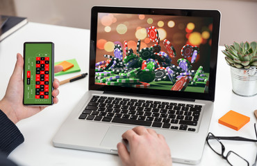 Online gambling, betting concept. Man working with a computer and holding holding a smartphone