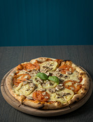 Fresh pizza with tomatoes, cheese and mushrooms on wooden table closeup
