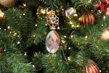 Christmas texture of crystal pendants on the background of green artificial fir branches of different sharpness with Golden lights and colorful toys. 