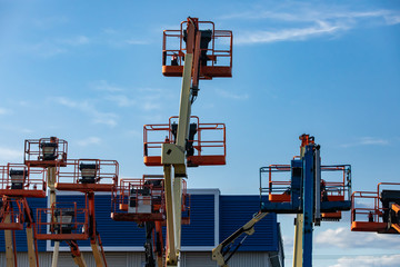 A construction industry storage unit and yard is seen with a group of mobile elevating work platforms, MEWP or cherry pickers, at rest and stored 