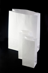  three white eco paper bags for products on a black background