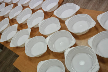 white plastic deep disposable plates stand on a wooden table. zero weist, recycling, global warming