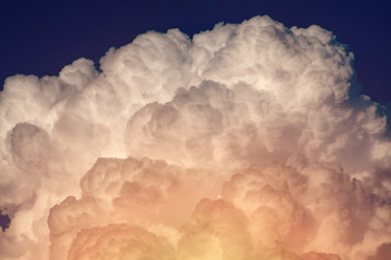 puffy fluffy clouds with yellow sunlight against a blue sky