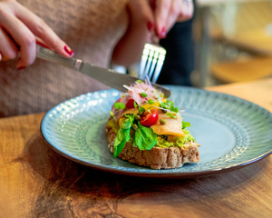 beautiful young girl sitting in front of a delicious healthy breakfast holding knife and fork
