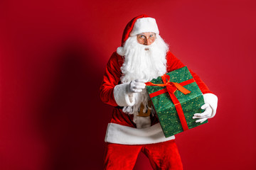 Photo of kind Santa Claus giving xmas present and looking at camera.