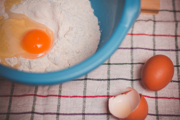 Vintage look on bowl with flour and raw egg ready for mixing and baking.