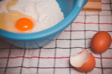 Vintage look on bowl with flour and raw egg ready for mixing and baking.