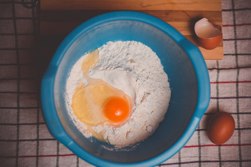 Vintage look on bowl with flour and raw egg ready for mixing and baking.