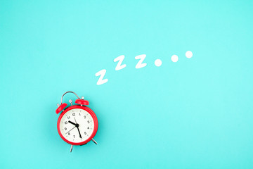 Snoring classic alarm clock on blue pastel trendy background. Flat lay, top view mock up