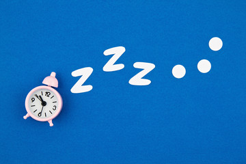 Snoring classic alarm clock on blue pastel trendy background. Flat lay, top view mock up