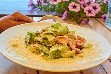 Caesar salad served in a white plate on a table