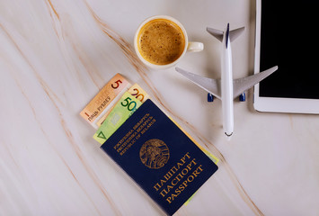 Belarusian passport and belarusian ruble money lying in the digital devices tablet with coffee and model airplane travel concept