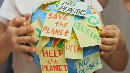 Family hands hug Earth globe with stickers with the message Save the Planet, Help and No Plastic.