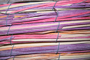Background from strips of rattan anthracite fastened together with metal wire horizontally pink...