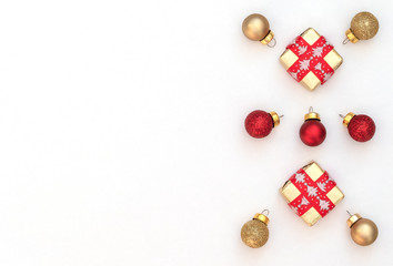 Two Christmas gift boxes with red ribbon and red and gold Xmas balls on white background. New Year greeting card. Christmas, New Year concept. Flat lay style with copy space.