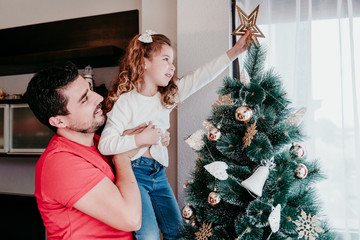 mother and son decorating christmas tree at home.