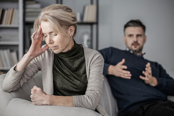 Senior depressed and tired wife with a headache in the middle of a conflict with a cheating husband
