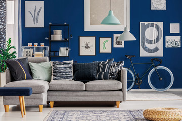 Blue living room with inspiring poster on the wall and grey corner sofa
