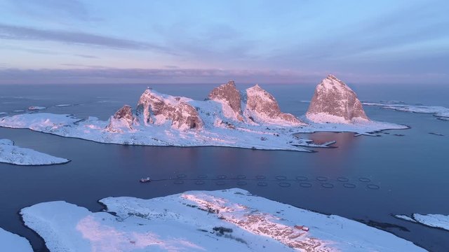 Winter sunset in Tr&aelig;na, iconic mountains of Sanna island, salmon farm, Nordland, Northern Norway, aerial drone shot