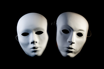 white masks of man and woman on a black background