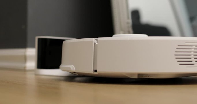 Robot vacuum cleaner is on charge. Smart home. Robot vacuum cleaner performs automatic cleaning of the apartment at a certain time. modern technology