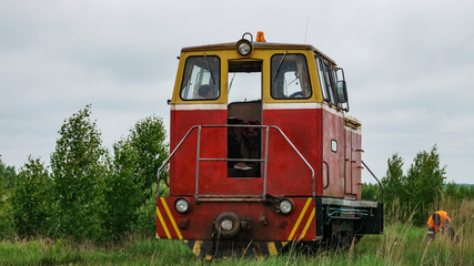 Obraz premium View of a narrow gauge railway locomotive on forest background. Extraction and transportations of peat.