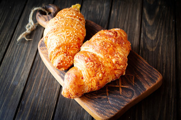 freshly baked golden croissants on dark wooden cutting board
