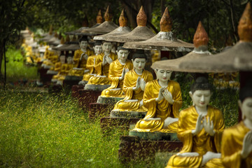 Many golden Buddha statues in a temple area in Myanmar.