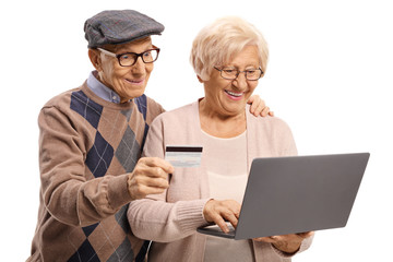 Senior couple using a payment card on the internet with a laptop computer