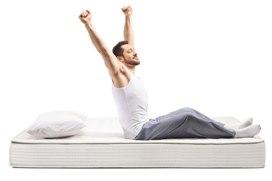 Young Man Stretching On A Bed Mattress