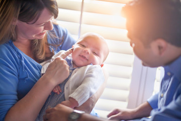 Happy Mixed Race Couple Enjoying Their Newborn Son In The Light of The Window.