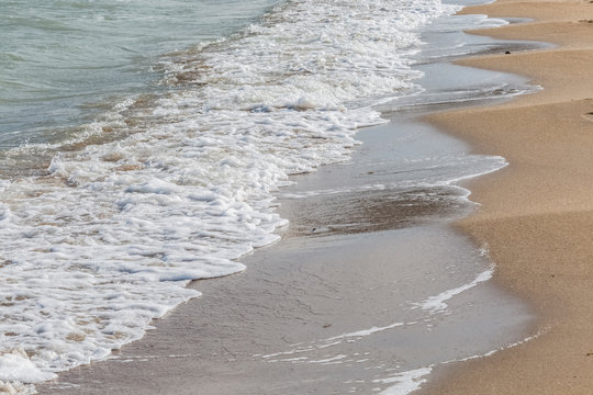 Foam sea wave on a sandy beach.