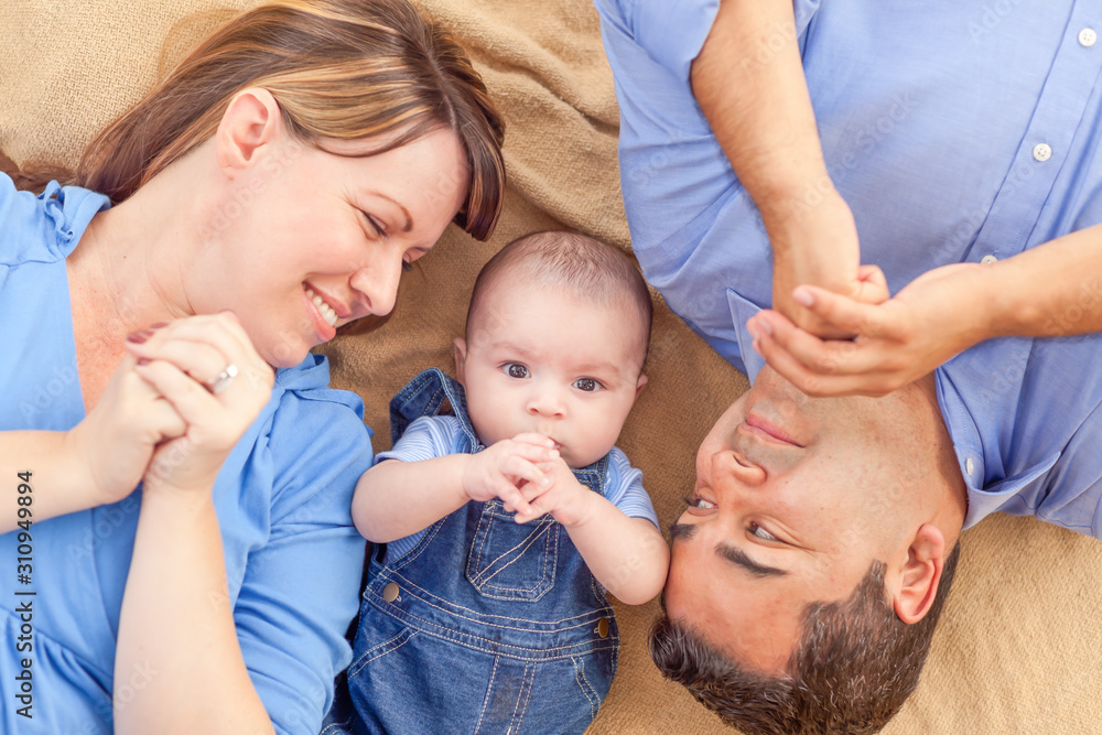 Wall mural Young Mixed Race Couple Laying With Their Infant On A Blanket