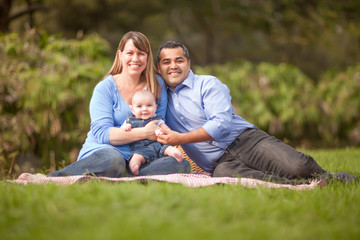 Happy Mixed Race Family Having a Picnic and Playing In The Park