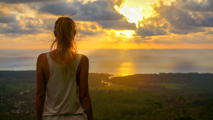 Inspiring scene of a woman standing at the viewpoint looking straight towards the pacific ocean...