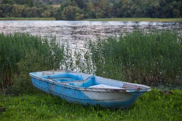 Old fishing boat on the grass by the river