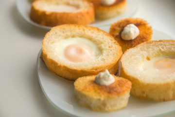 fried eggs baked in round bread with croutons on a white plate top view close up